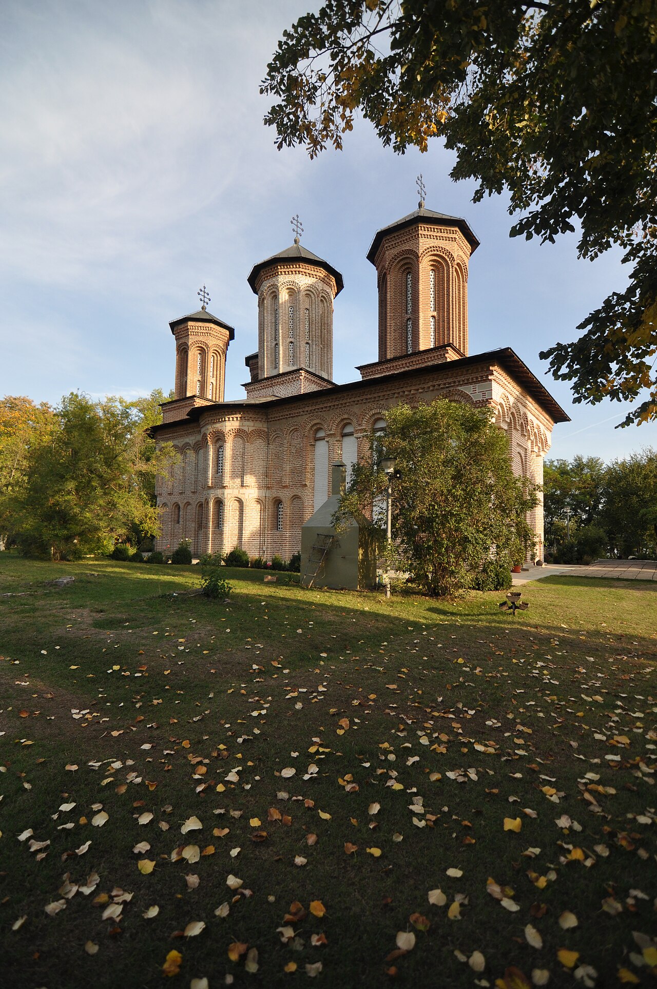 Biserica văzută din curtea insulei, între arbori.
