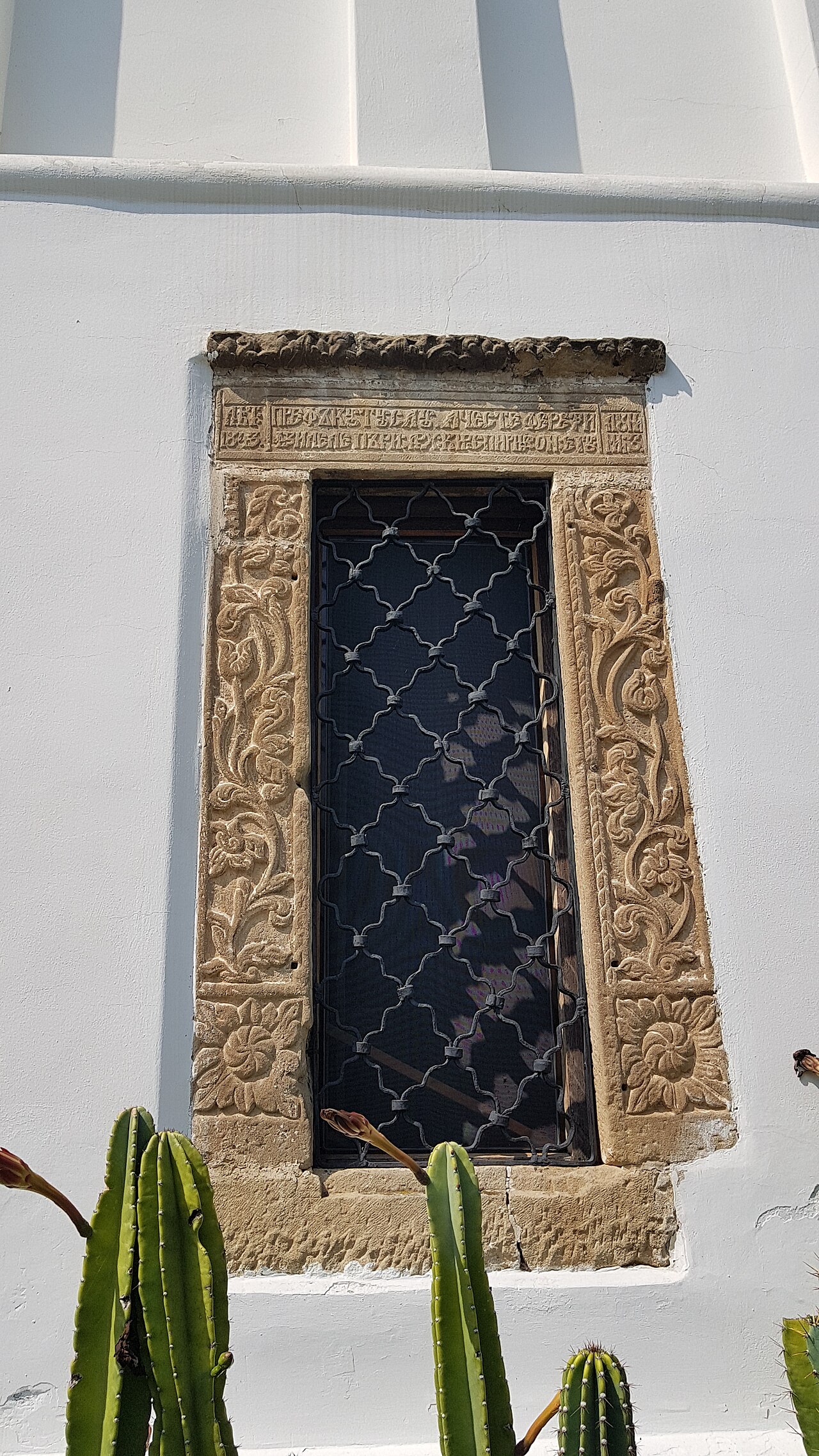 Ancadramentul sculptat și grilajul ferestrei bisericii.