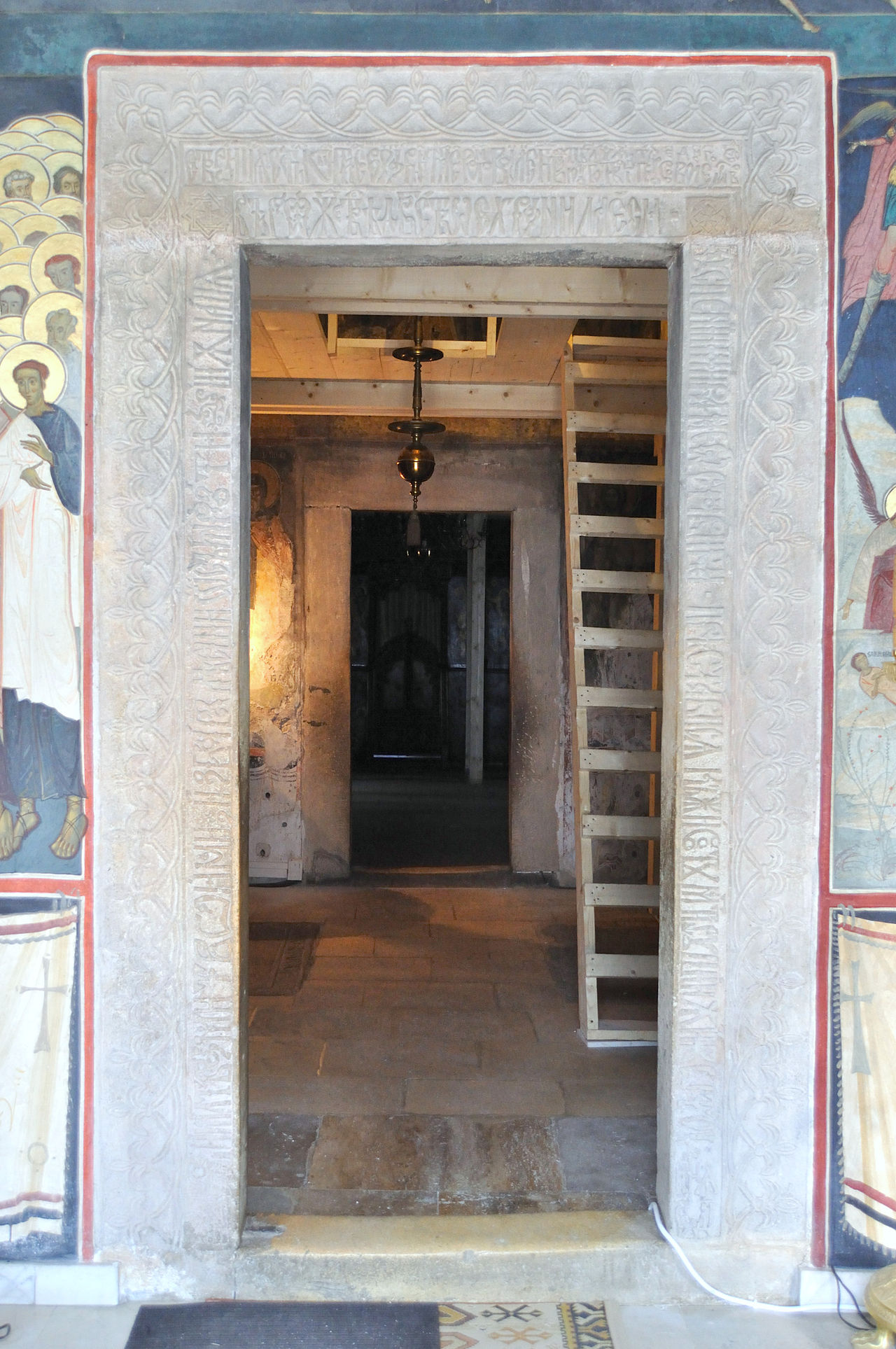 Portal de piatră și decor pictat la intrarea în biserică.