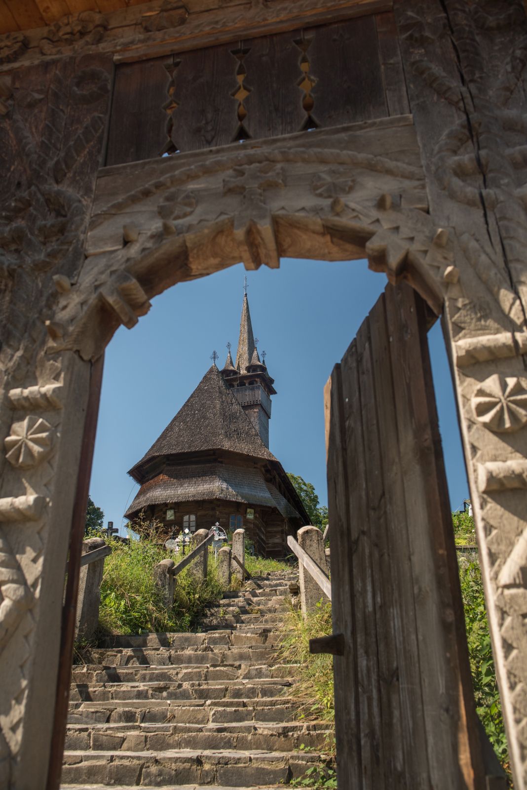 Poarta de lemn și scara spre biserica Josani din cimitir.