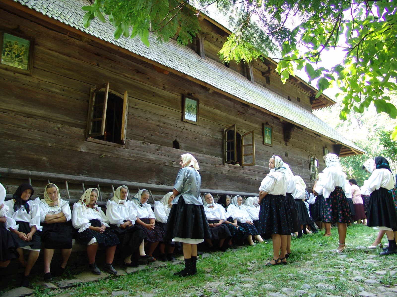 Fațada de bârne și ferestrele; oamenii ascund soclul.