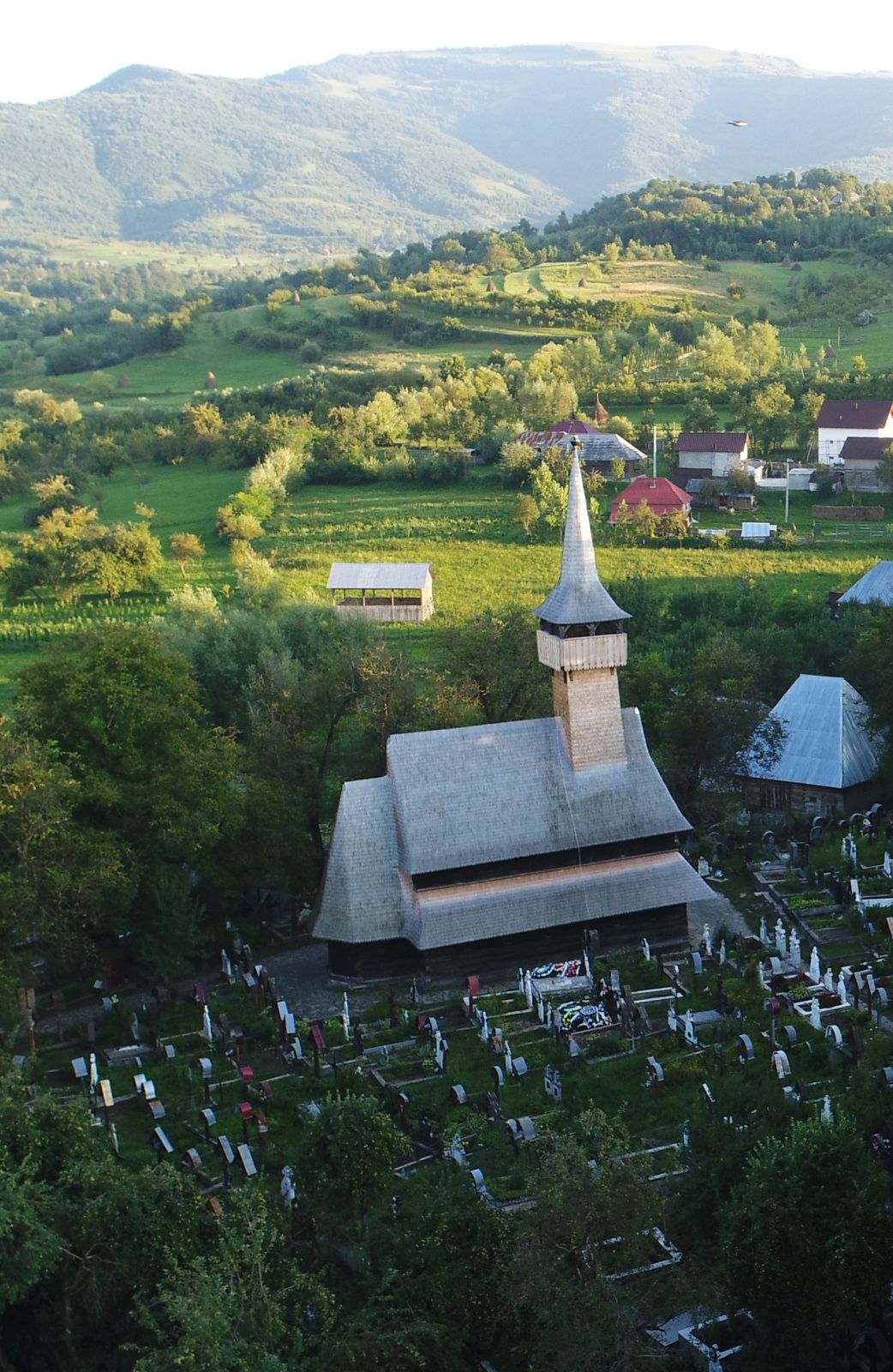 Vedere aeriană oblică a bisericii Ieud Deal, cimitir și sat.