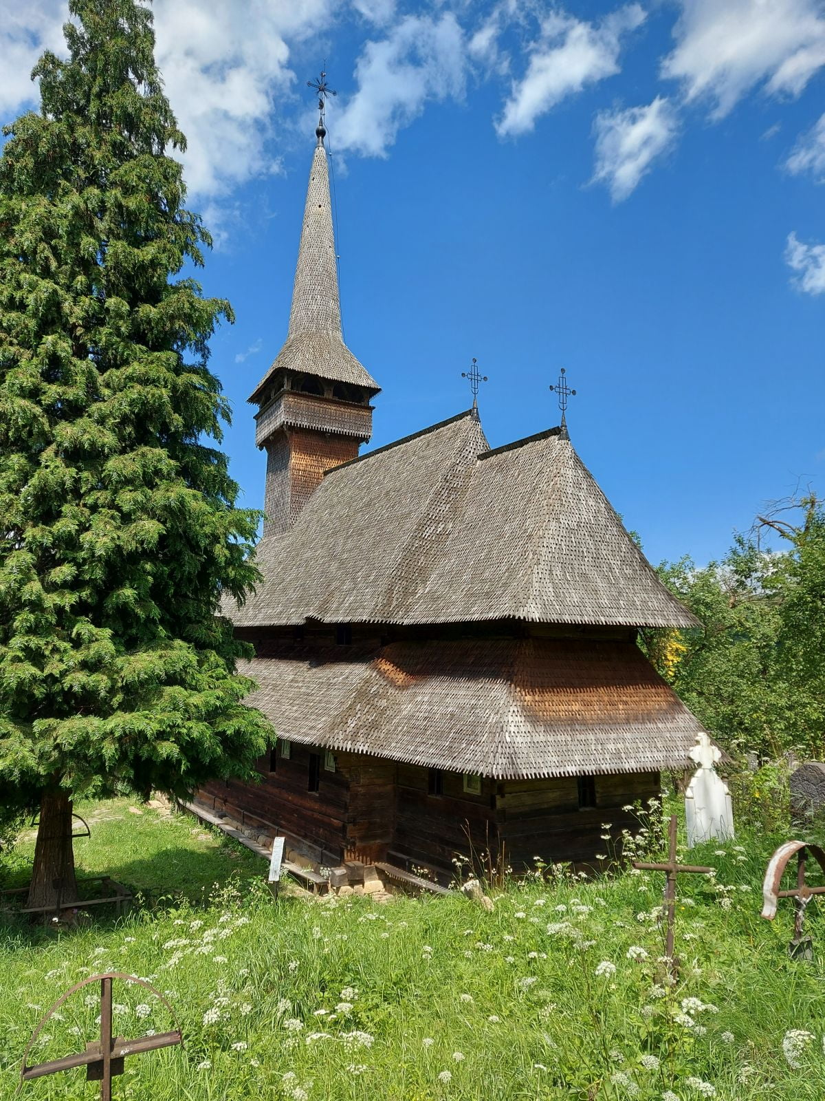 Biserica UNESCO din Poienile Izei: turn, pereți de bârne și acoperiș cu două poale.