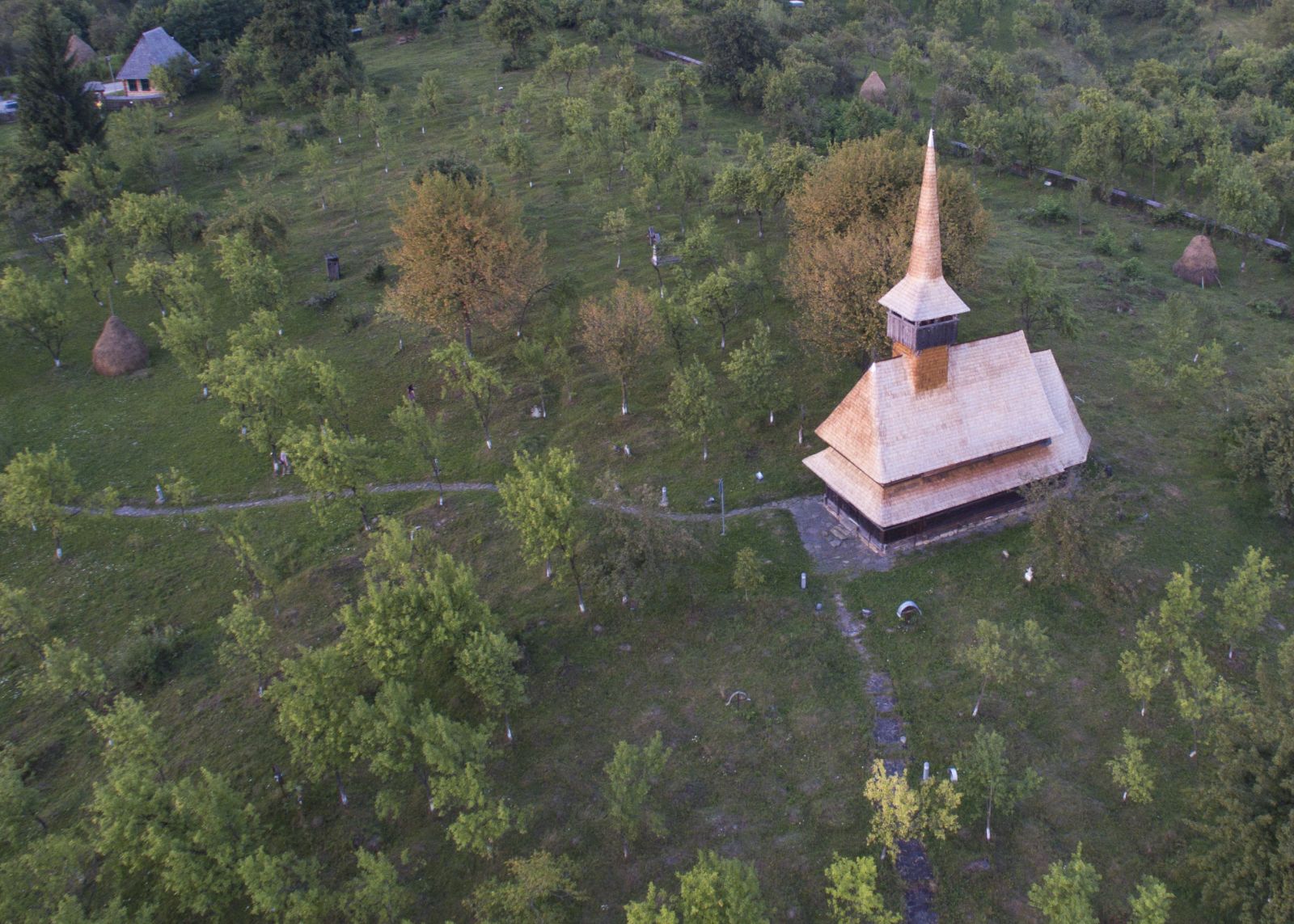 Vedere aeriană oblică asupra bisericii istorice, izolată între arbori pe dealul Jbâr.